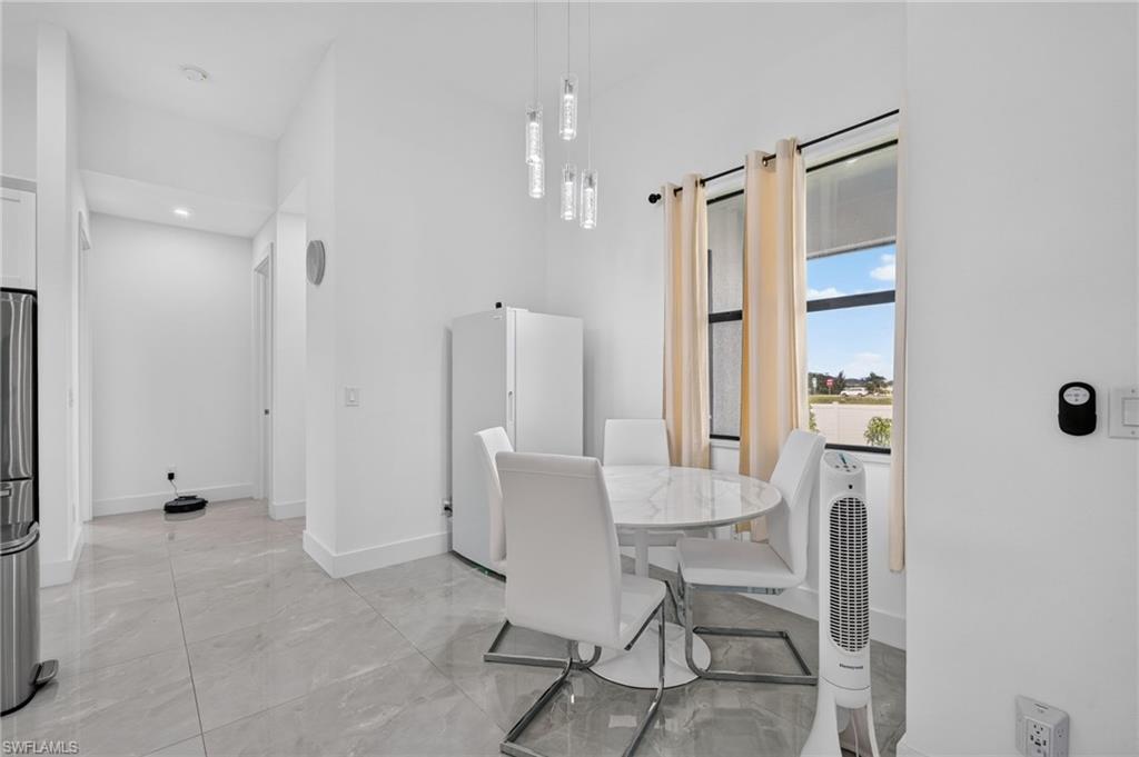 Bright interior space featuring a window with exterior views, light tile flooring, and a modern pendant light fixture