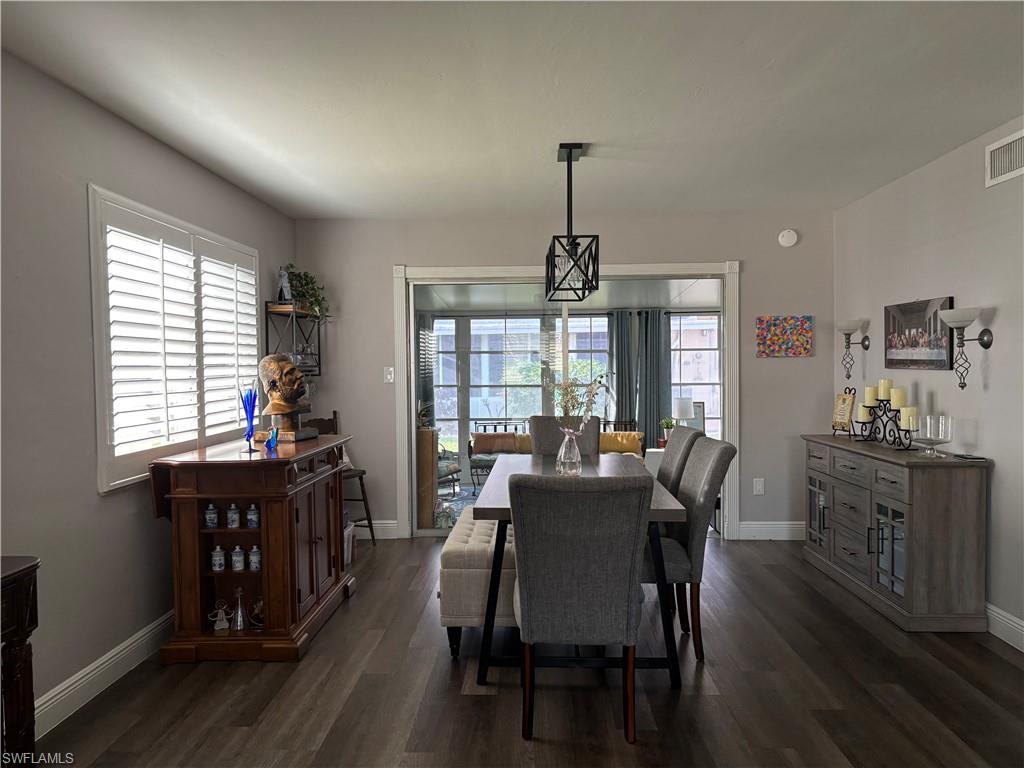 Dining space with wood-finish flooring, white plantation shutters, and a contemporary linear pendant light fixture
