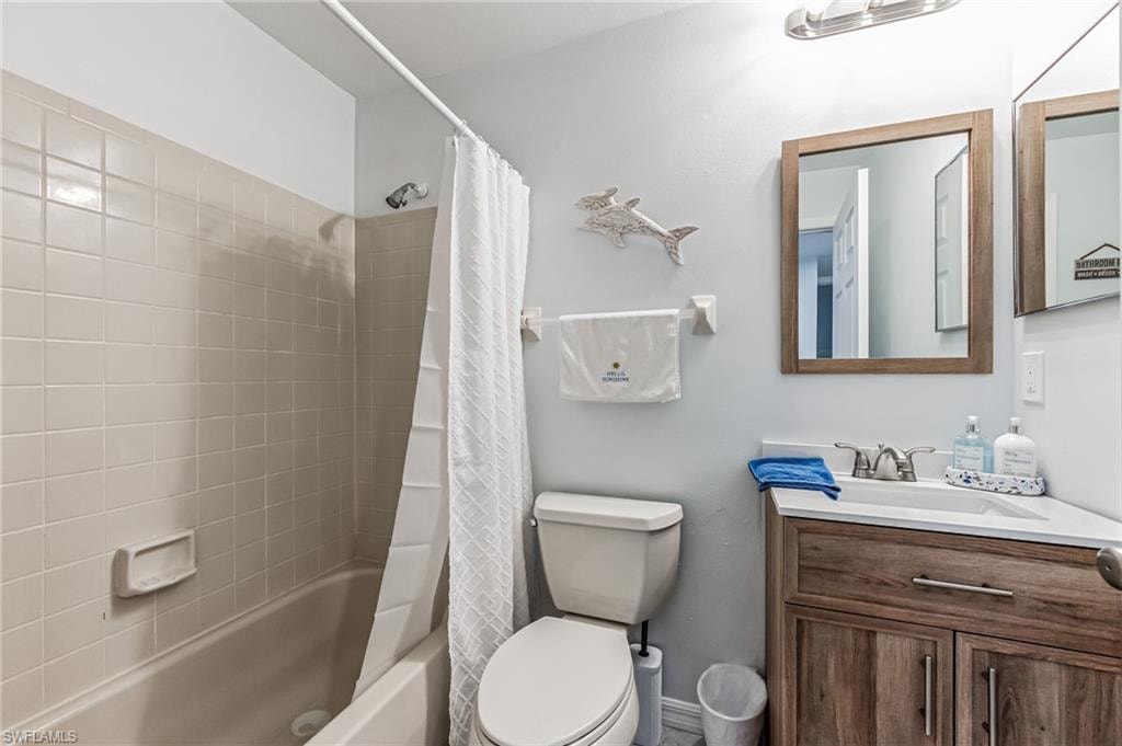 Full bathroom featuring a single vanity with wood-finish cabinetry, a white countertop, and a chrome faucet