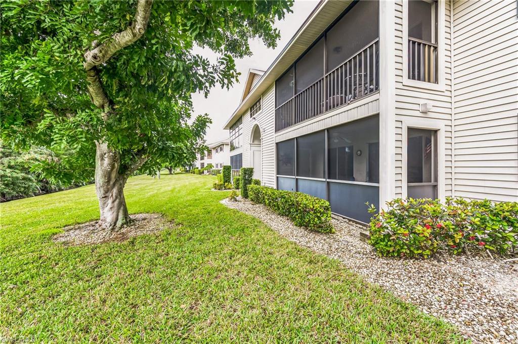 Expansive green lawn featuring mature trees, landscaped shrubbery, and a gravel border