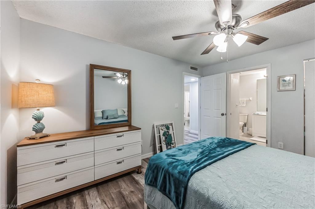 Bedroom featuring wood-finish flooring, a ceiling fan with integrated lighting, and a white six-drawer dresser with a wood-frame mirror