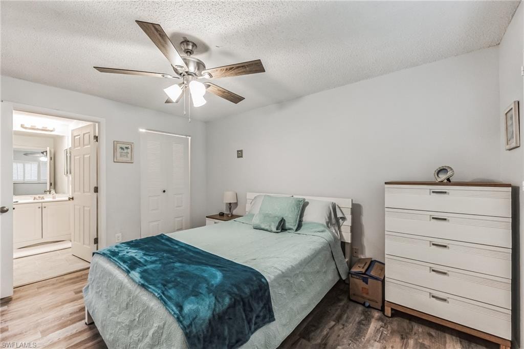 Bedroom featuring wood-finish flooring, a ceiling fan with light fixture, and a built-in closet with bifold doors