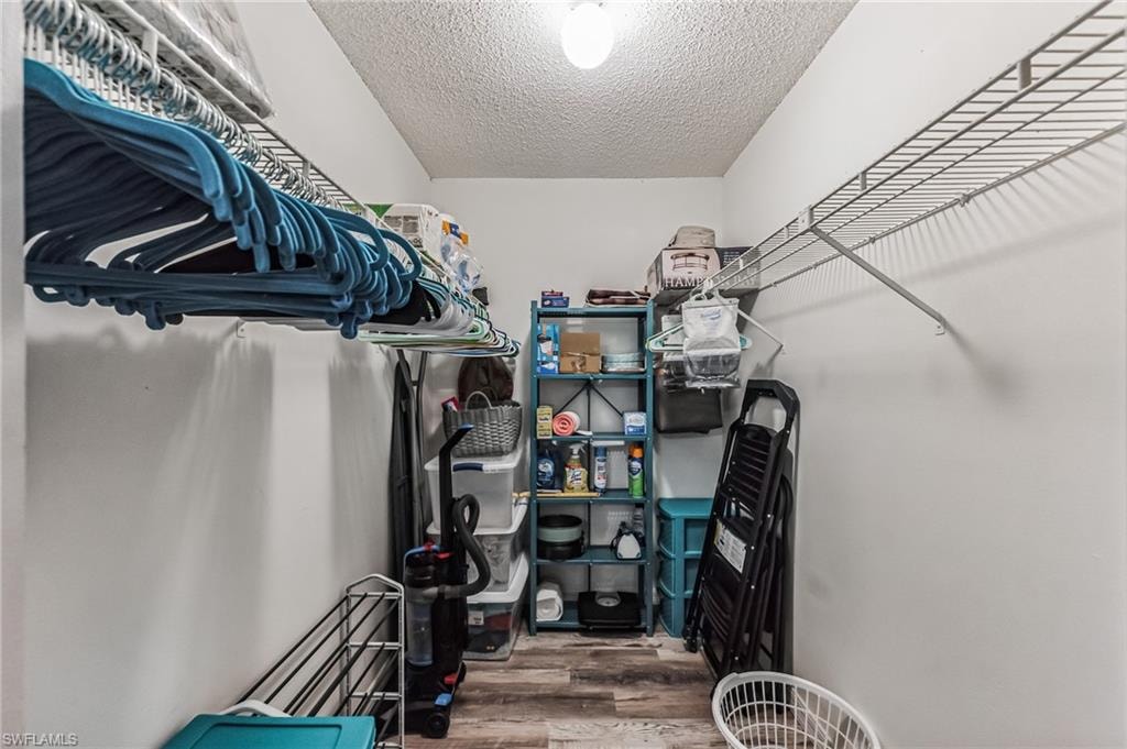 Walk-in closet featuring wire shelving, hanging rods, light wood-finish flooring, and white walls
