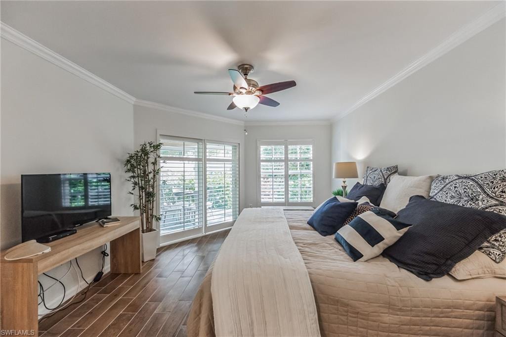 Spacious room featuring wood-finish flooring, two sets of sliding glass doors with plantation shutters, a ceiling fan with integrated lighting, and crown molding