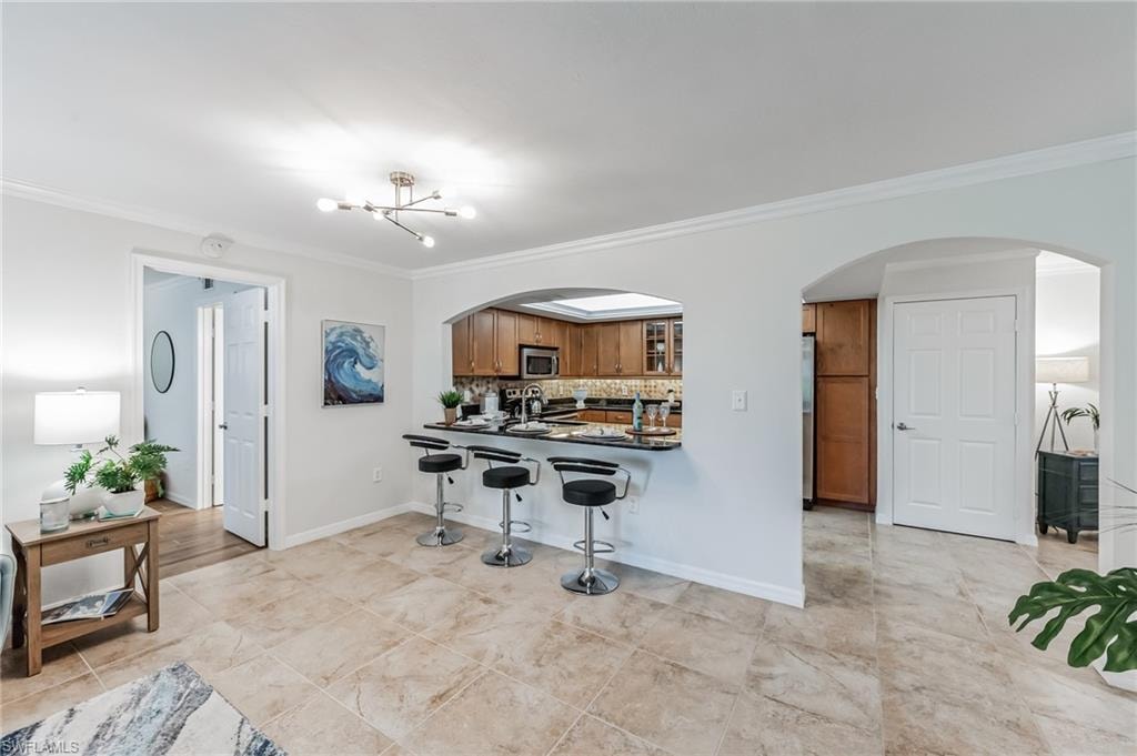 Kitchen pass-through with breakfast bar featuring a dark countertop, wood cabinetry, and a tile backsplash