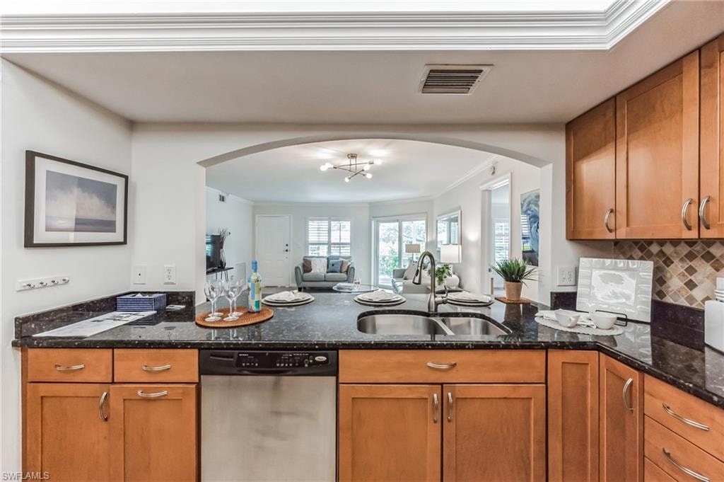 Kitchen with dark granite countertops, wood cabinetry, and a tile backsplash
