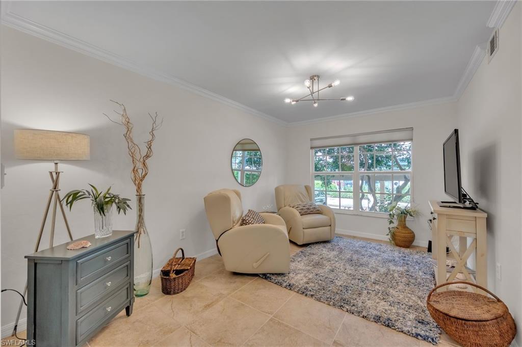 Bright interior space featuring large windows, crown molding, a modern multi-light ceiling fixture, and neutral tile flooring