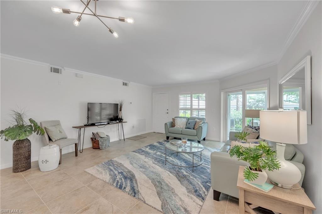 Bright living area featuring tile flooring, crown molding, and a contemporary multi-bulb ceiling fixture