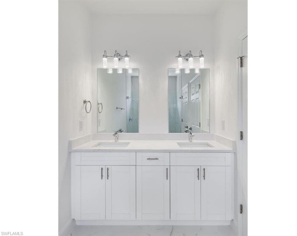 Dual vanity featuring white shaker-style cabinetry, undermount sinks, and stone countertops