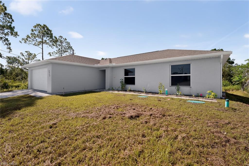 Contemporary single-story residence featuring a two-car garage, light-colored stucco exterior, and a brown shingle roof