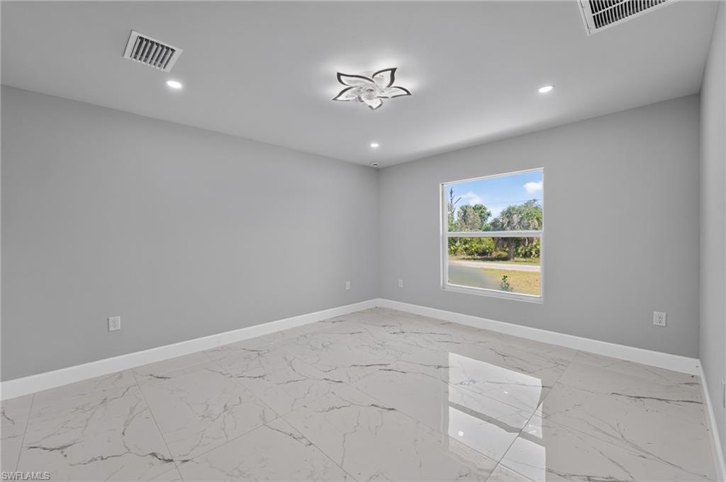 Spacious room featuring large format tile flooring, a prominent window with a white frame, recessed lighting, and a decorative flush-mount ceiling fixture