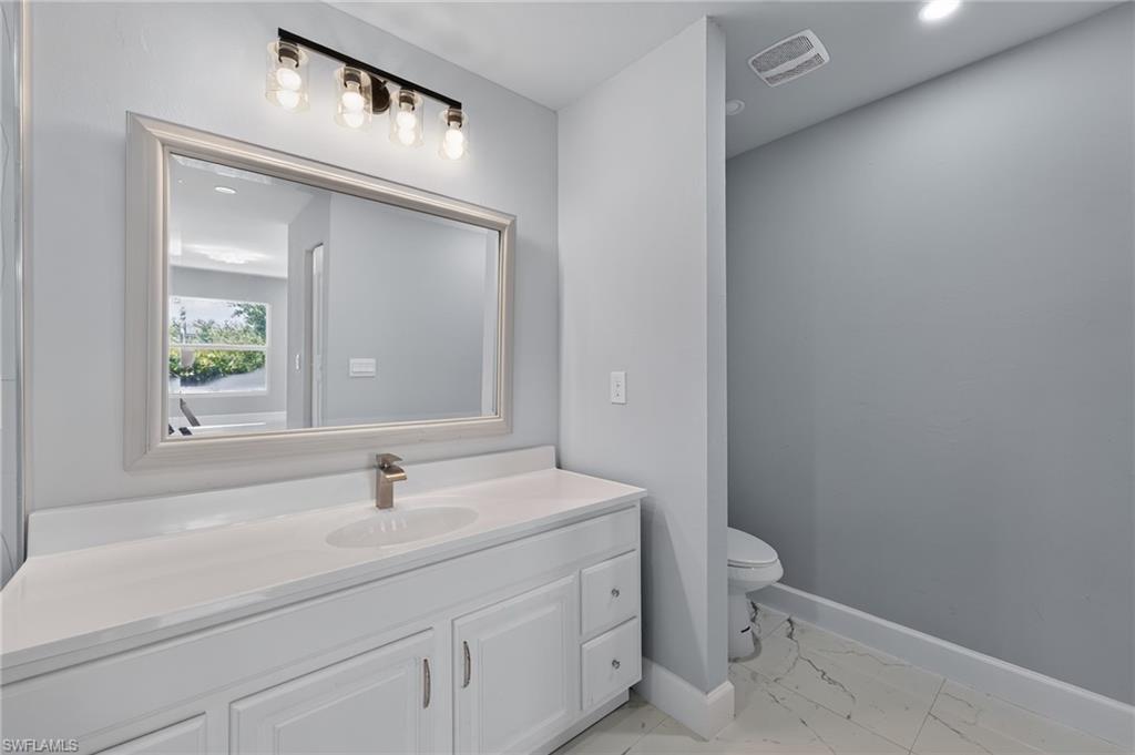 Bathroom vanity featuring a framed mirror, a five-light fixture, and a single basin sink with a brushed nickel faucet