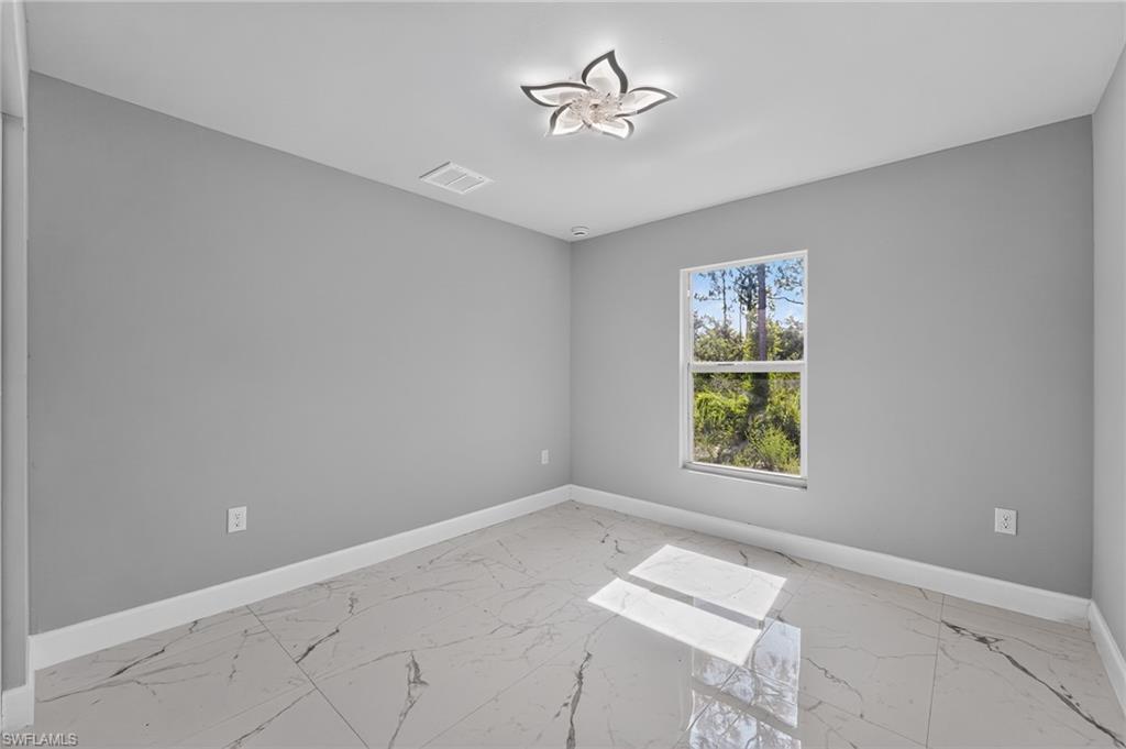 Room featuring large format marble-look tile flooring, light gray wall paint, and white trim