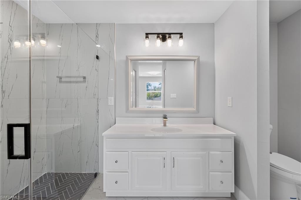 White vanity with a single basin sink, light countertop, and framed mirror