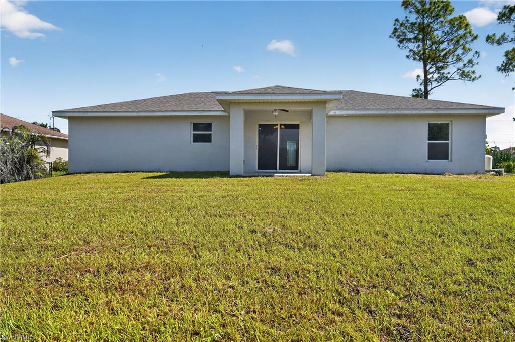 Expansive rear yard featuring a level lawn and a single-story property with a light-colored stucco exterior