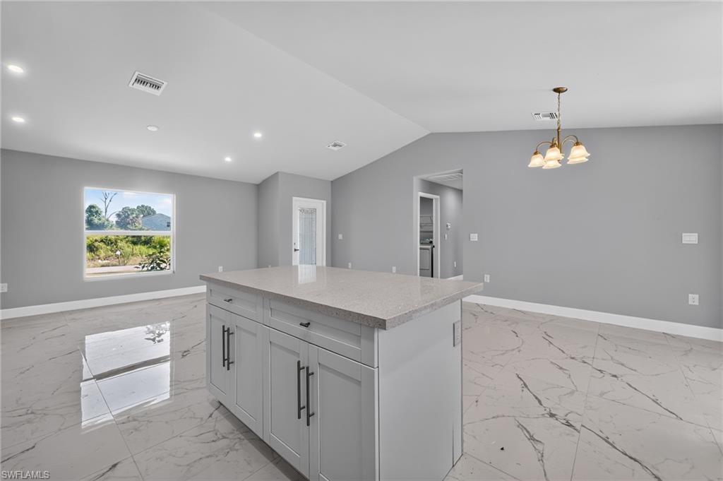 Central kitchen island featuring a light gray countertop, light gray cabinetry, and matte black hardware