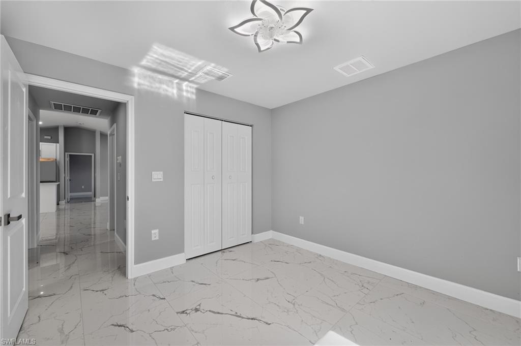 Room featuring large format white tile flooring with gray veining, light gray walls, and white baseboards