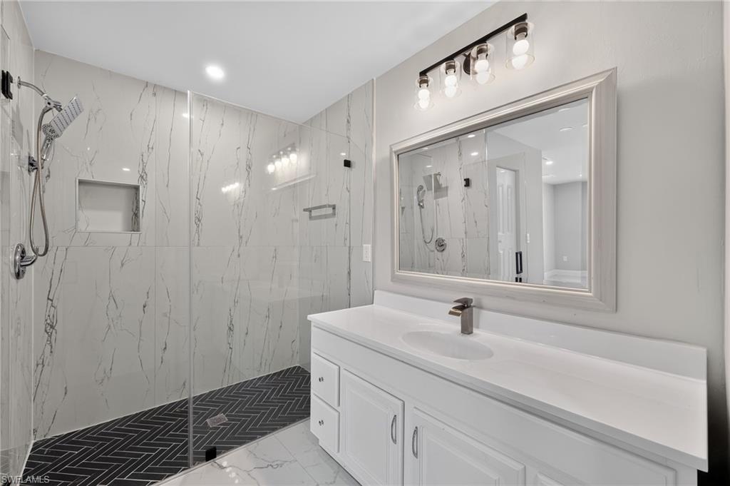 Contemporary bathroom featuring a spacious walk-in shower with clear glass enclosure and black herringbone tile floor