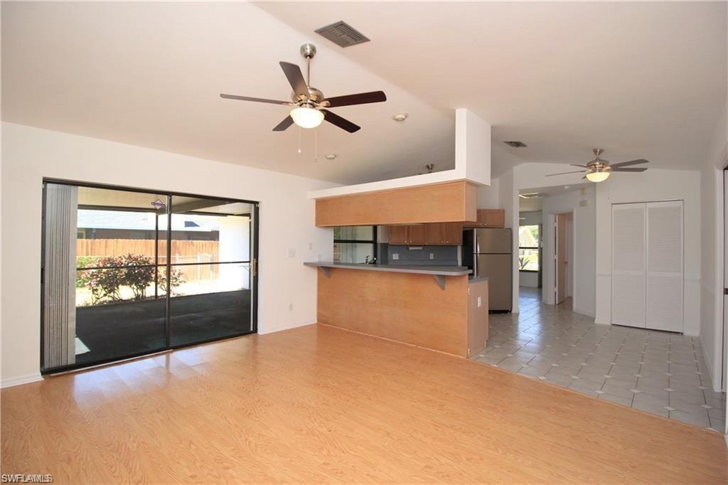 Unfurnished living room featuring ceiling fan, lofted ceiling, and light wood-type flooring