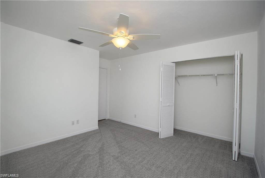 Unfurnished bedroom featuring a closet, ceiling fan, and dark carpet