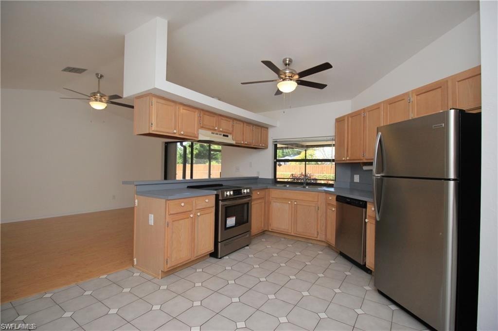 Kitchen featuring light tile floors, ceiling fan, vaulted ceiling, and stainless steel appliances