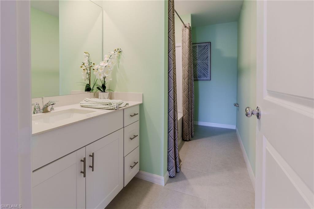 Bathroom with a single basin vanity featuring white cabinetry and light-toned countertop, a large wall mirror, and light green walls