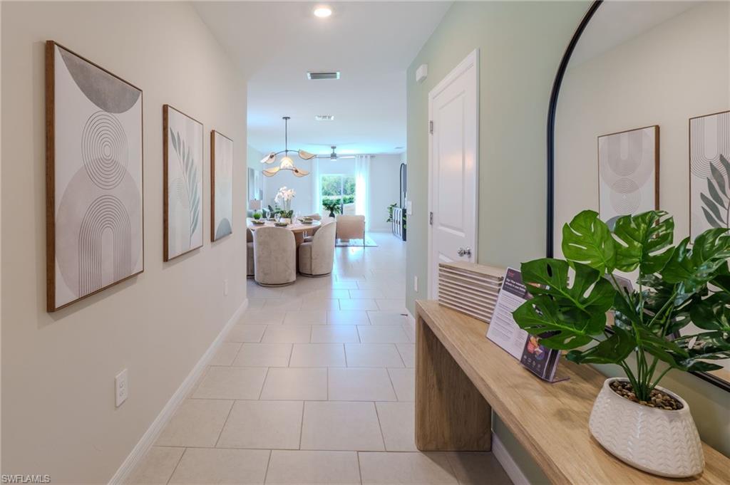 Open-concept hallway featuring light-toned tile flooring, recessed lighting, and a neutral color palette