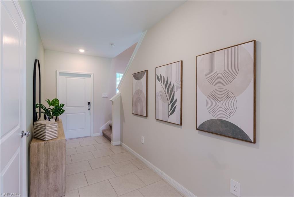 Entryway featuring light-toned tile flooring, white baseboards, and a paneled entry door