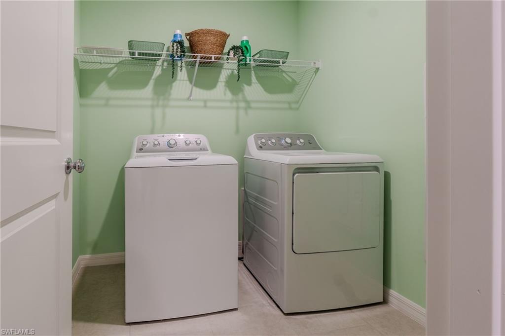 Dedicated laundry area featuring a washer and dryer, light green walls, and a wire shelving unit