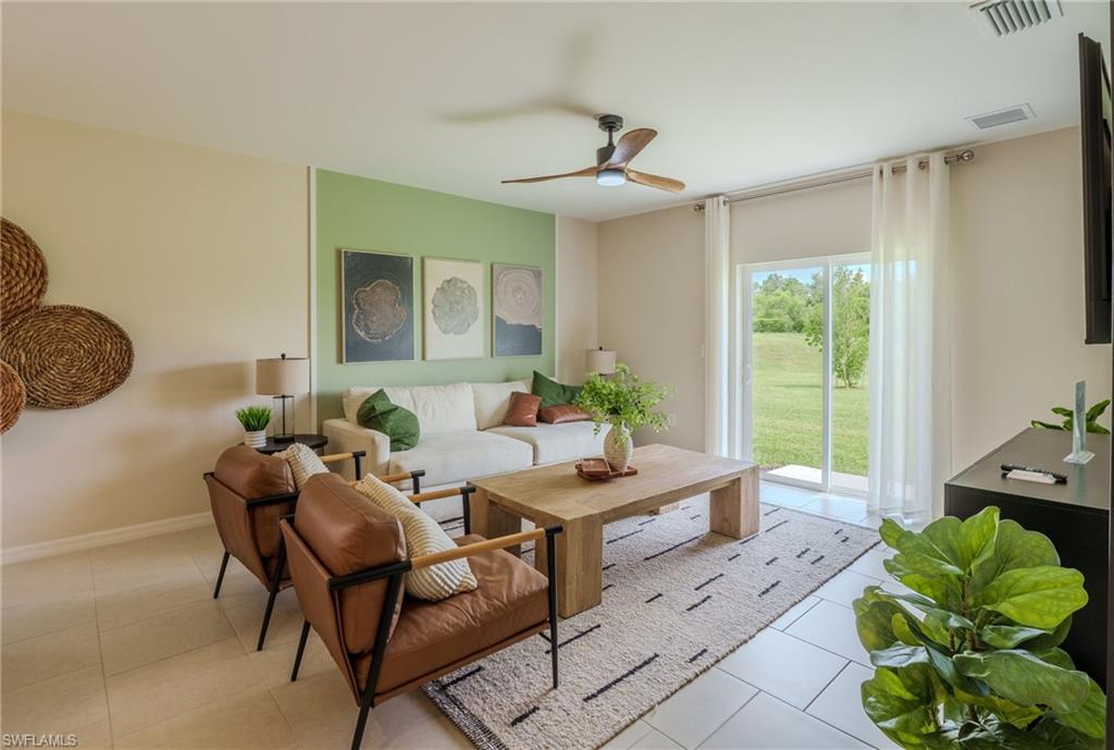 Open-concept living space featuring a sliding glass door, overhead ceiling fan, light-toned tile flooring, and a green accent wall