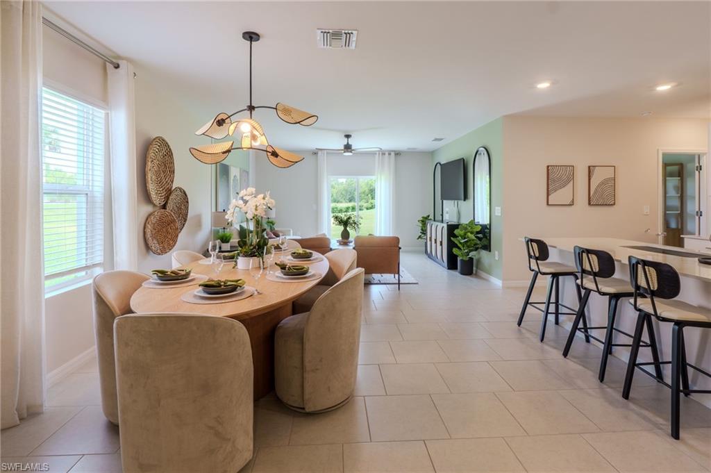 Open-concept dining area featuring a distinctive overhead light fixture and neutral tile flooring