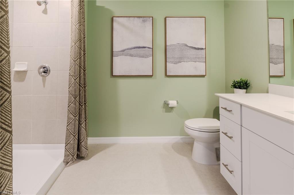 Full bathroom featuring a white single vanity with a solid surface countertop, an undermount sink, and brushed nickel hardware