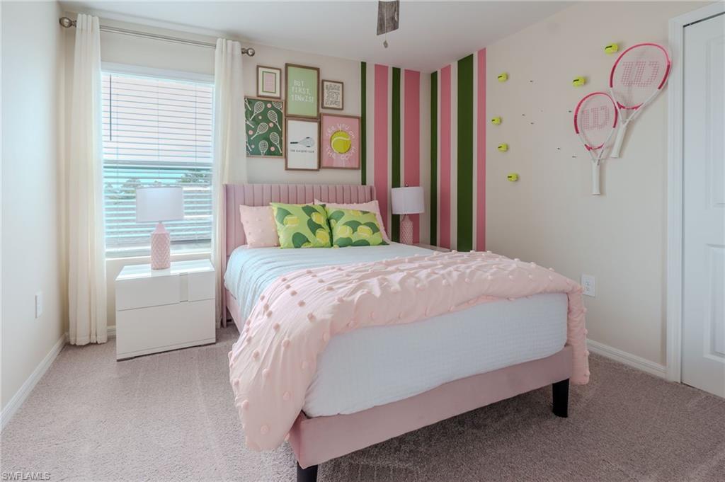 Bright bedroom featuring neutral carpeting, a large window with blinds and curtains, and a painted accent wall with vertical stripes