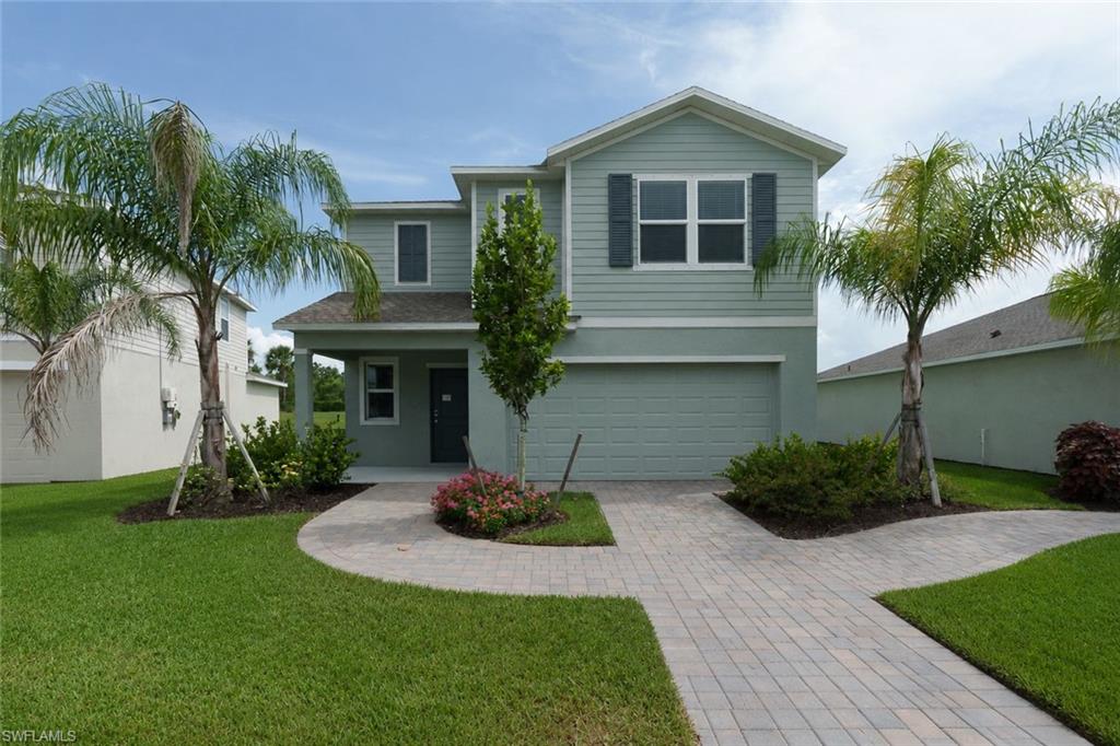 Two-story home with light green siding and dark shutters, featuring an integrated garage