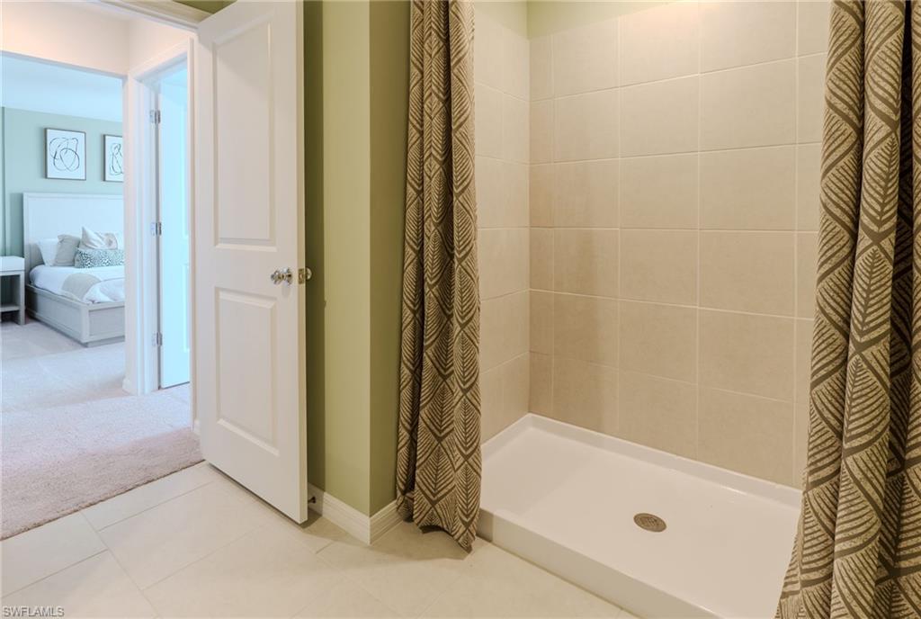 Shower enclosure featuring light-toned tile walls and a white shower base