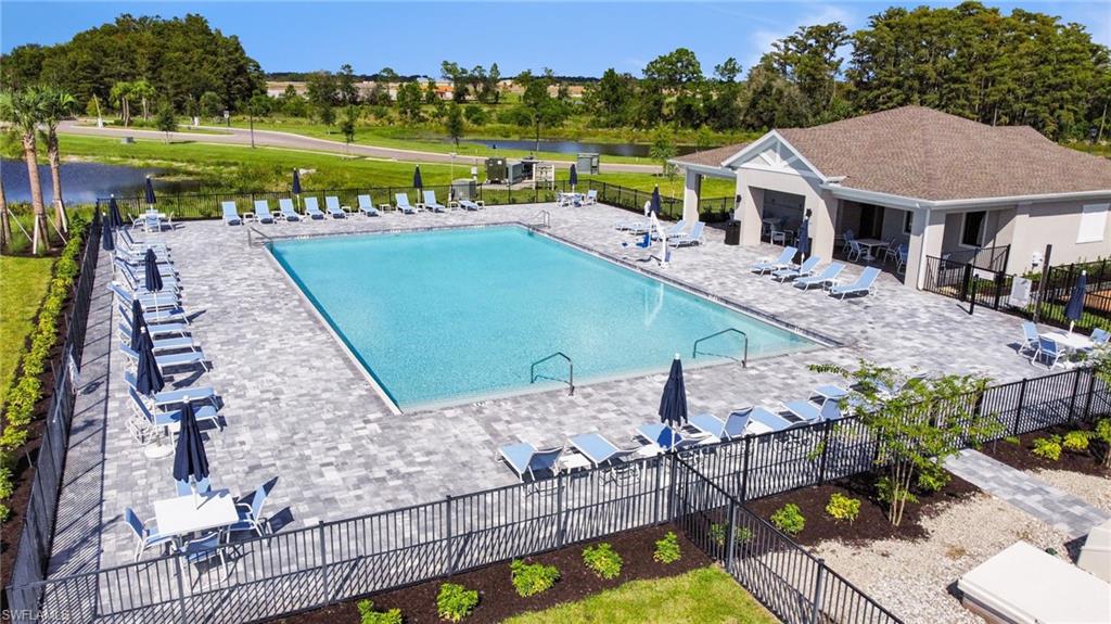 Expansive community pool with a surrounding paver deck, a covered lounge area, and direct access to a clubhouse