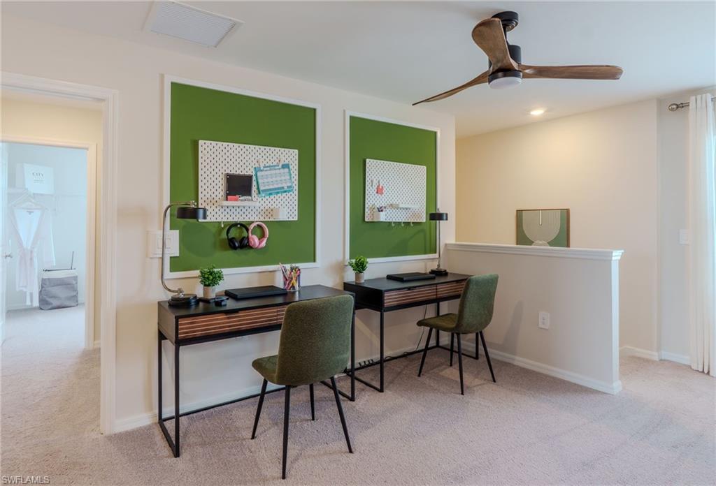 Carpeted room featuring a ceiling fan with integrated lighting, a low wall partition, and a doorway leading to an additional space