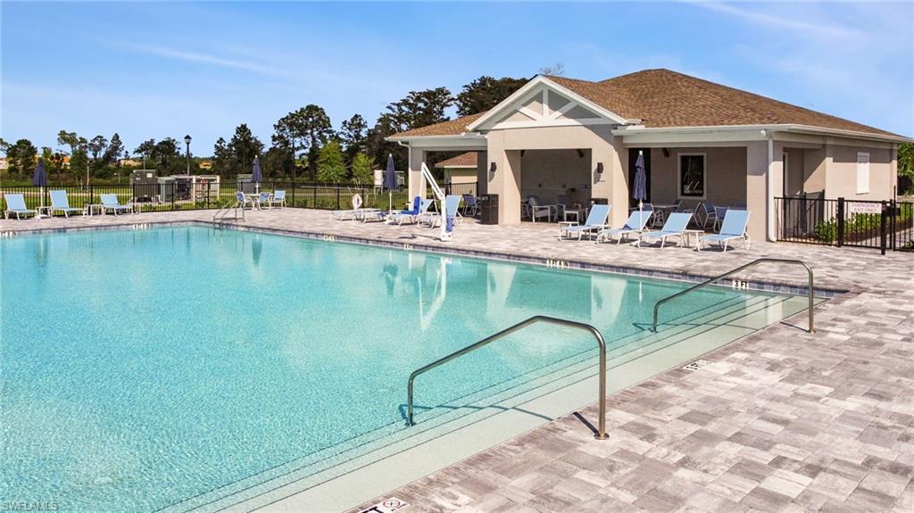 Expansive outdoor swimming pool featuring a light blue finish, integrated steps, and stainless steel handrails