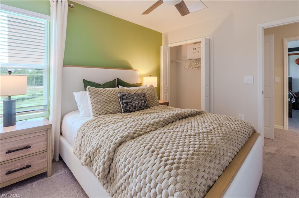 Bedroom featuring a light green accent wall, carpeted flooring, and a ceiling fan