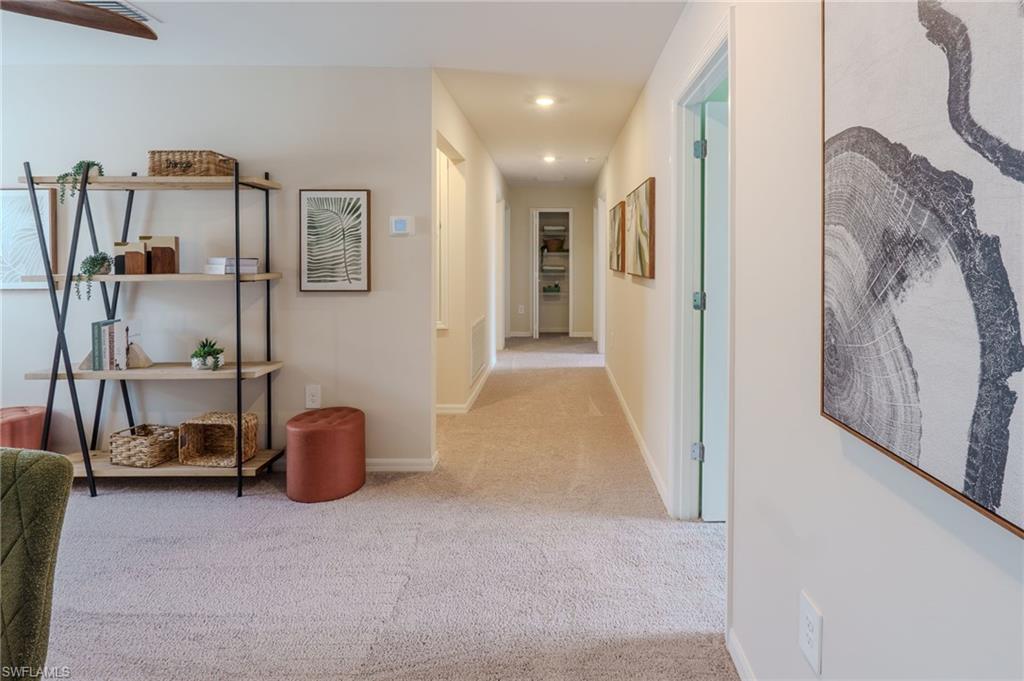 Carpeted hallway with recessed lighting and neutral wall tones