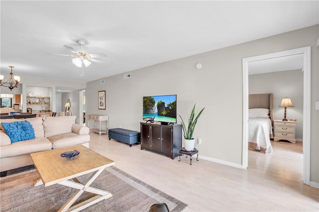 Living room featuring ceiling fan with notable chandelier and light hardwood / wood-style floors