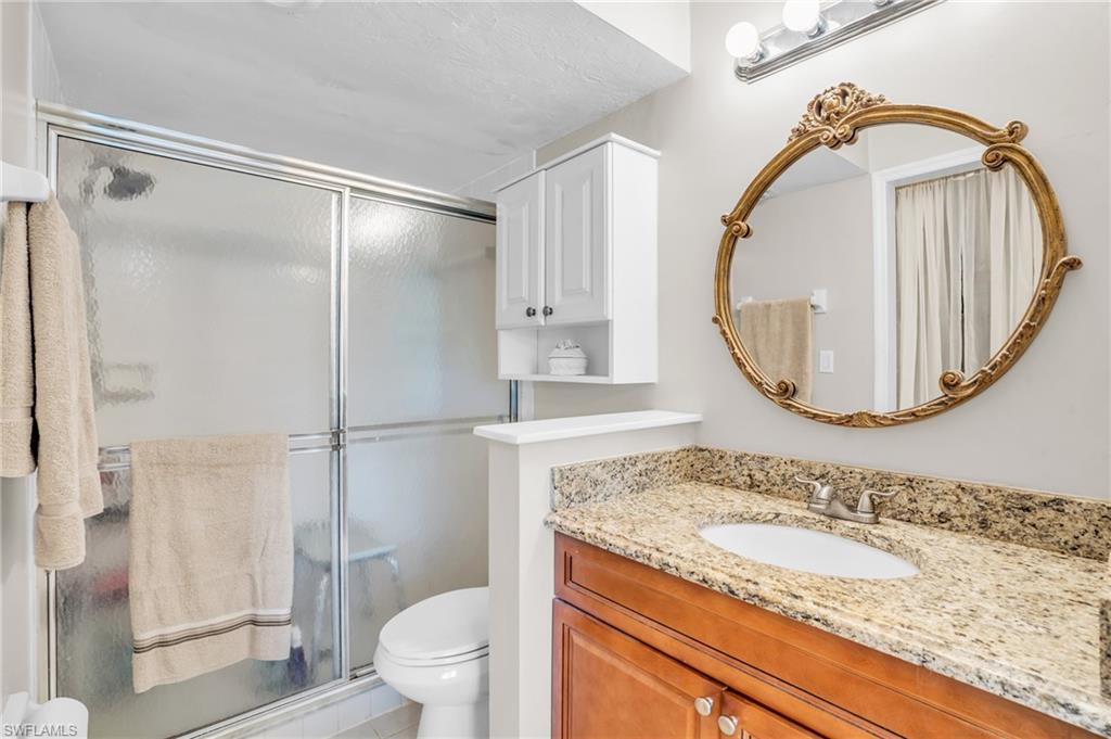 Bathroom featuring a shower with door, toilet, and vanity