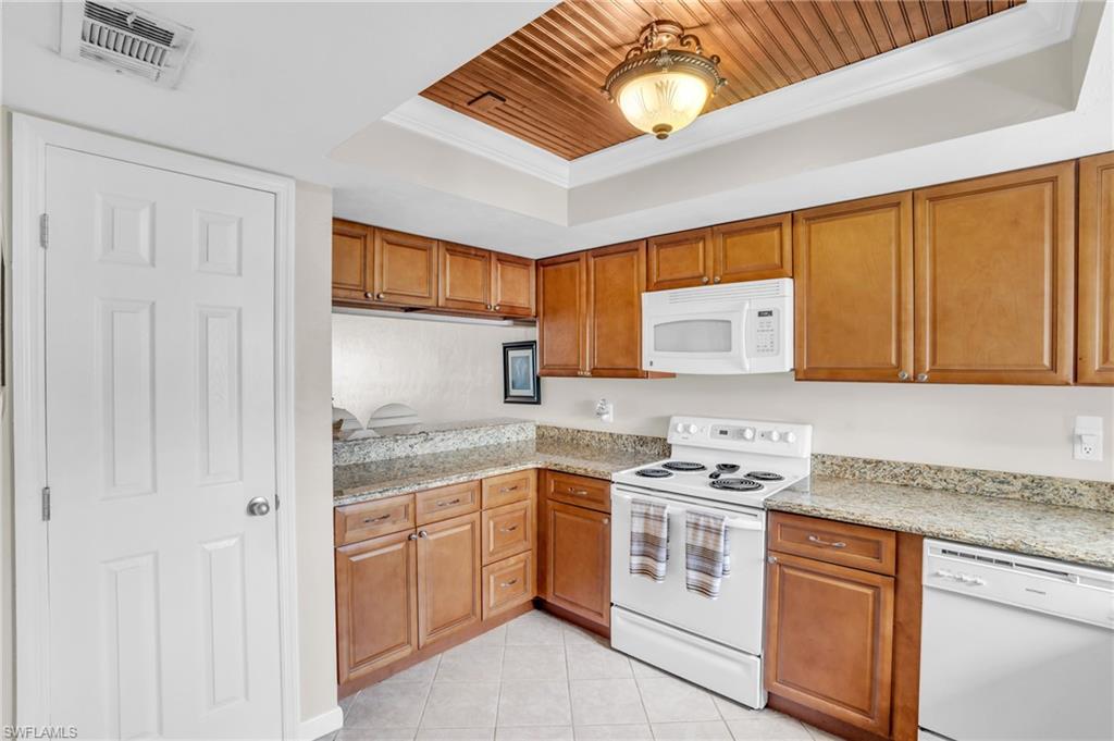 Kitchen featuring wooden ceiling, white appliances, light stone countertops, a raised ceiling, and light tile patterned floors