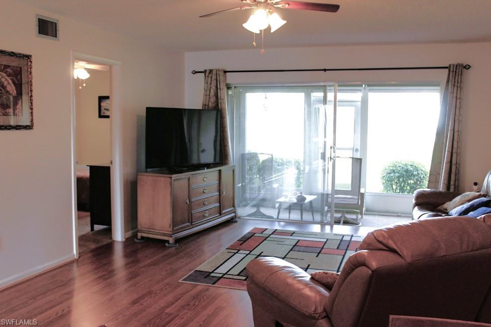 Living area featuring a ceiling fan and dark wood-style floors