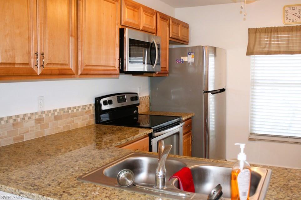 Kitchen with appliances with stainless steel finishes and light stone countertops