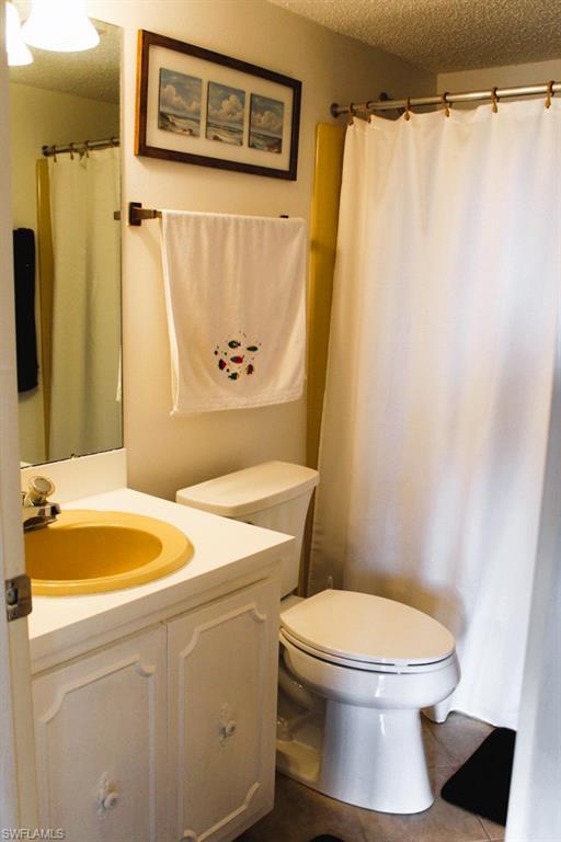 Full bath featuring a textured ceiling, vanity, a shower with shower curtain, and tile patterned floors