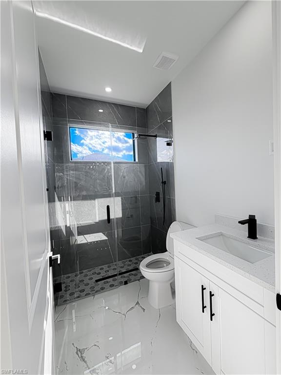 Modern bathroom featuring a glass-enclosed shower with dark tile surround, a contrasting hexagonal tile shower floor, and a rectangular window
