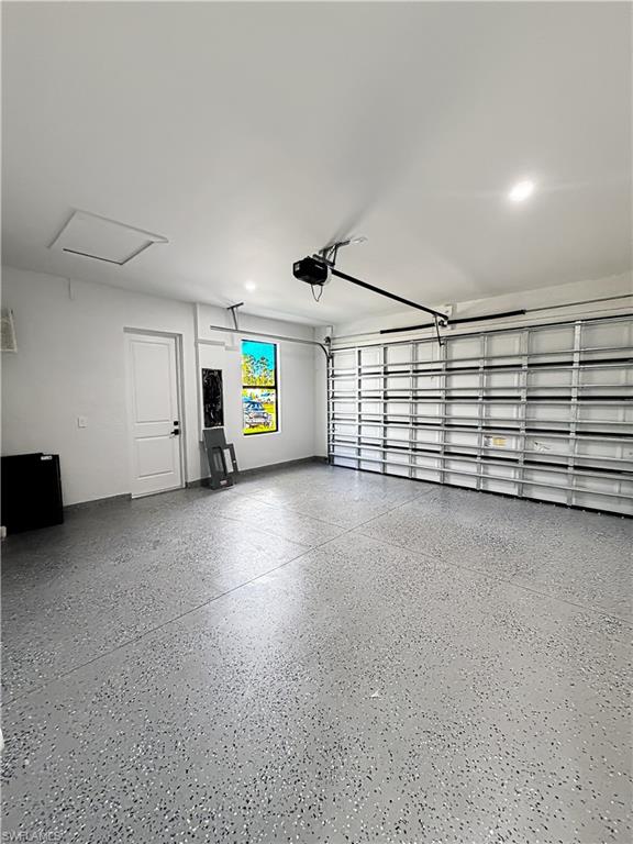 Spacious garage featuring a durable epoxy-coated floor, bright recessed lighting, a window for natural illumination, and an access door