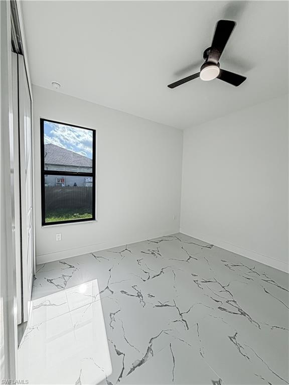 Spacious room featuring large format tile flooring with a marble-effect pattern, a contemporary ceiling fan with integrated lighting, and a window providing natural illumination