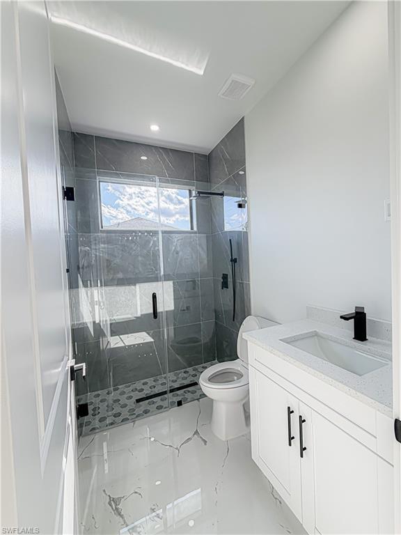 Modern bathroom featuring a glass-enclosed shower with dark tile surround, a white vanity with a light speckled countertop, a rectangular sink, and matte black fixtures